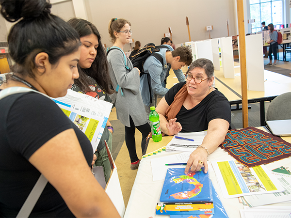A female instructor points to places on a map of Latin America as students look on during a study abroad information session.